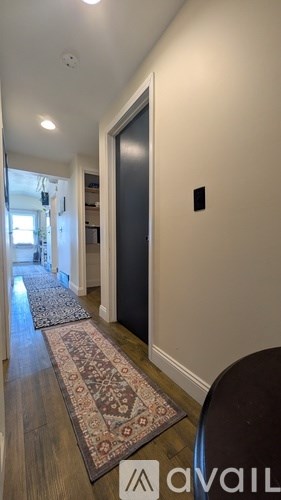 A hallway with a rug on the floor and a door on the right.