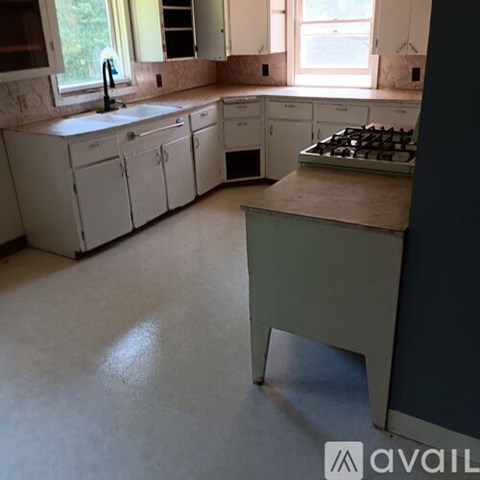 A kitchen with white cabinets and a window.