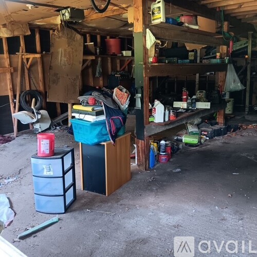 A cluttered garage with various items on the floor and shelves.