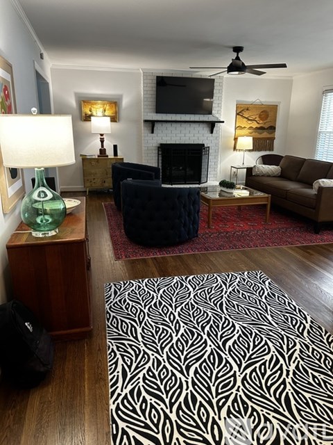 A living room with a black couch and a patterned rug.