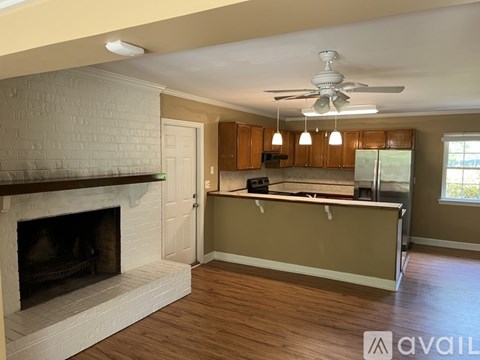 A living room with a fireplace and a kitchen area in the background.