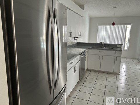 A modern kitchen with a stainless steel refrigerator and white cabinets.
