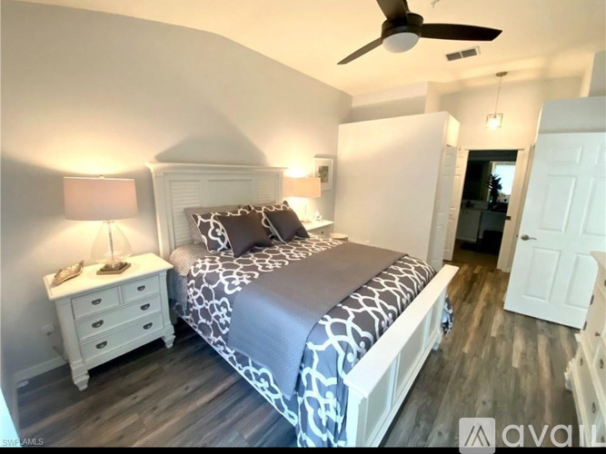 A bedroom with a bed, nightstand, and a ceiling fan.
