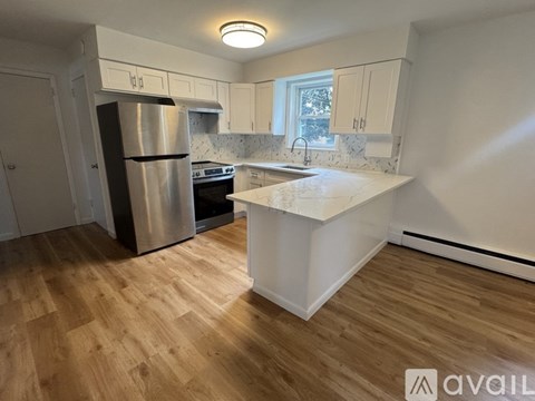 A kitchen with a stainless steel refrigerator and wooden flooring.