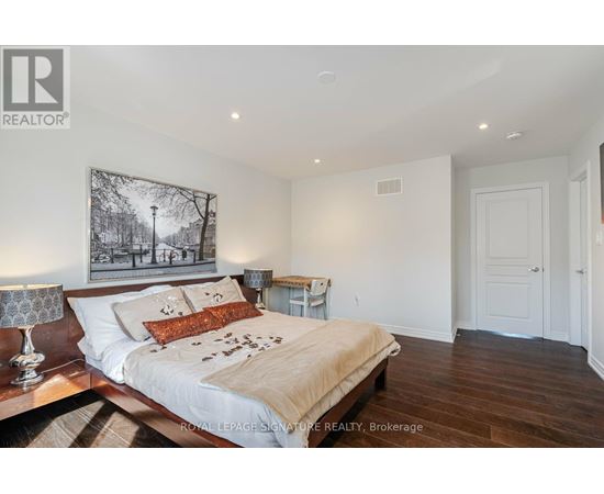 A bedroom with a large bed and a painting on the wall.