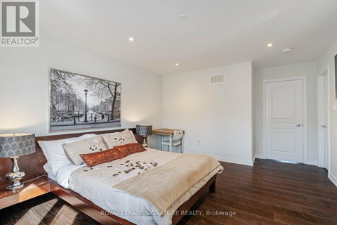 A bedroom with a large bed and a painting on the wall.