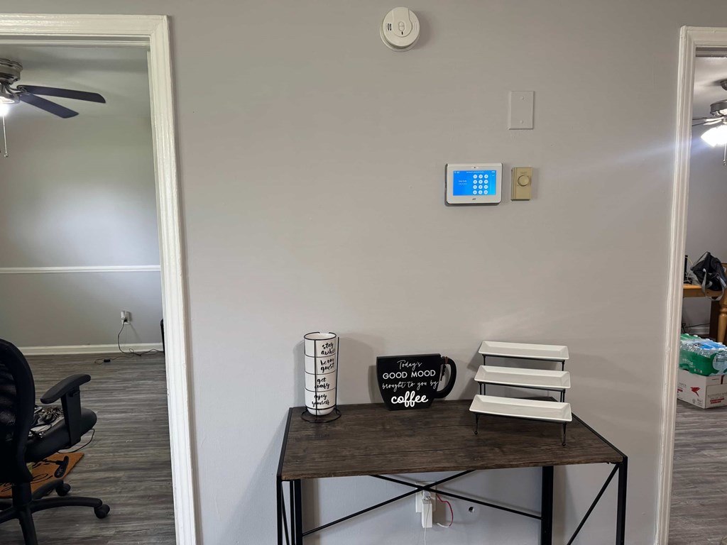 A room with a table, a chair, and a wall-mounted device.