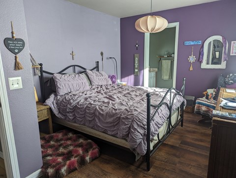 A bedroom with purple walls and a bed with a purple comforter.