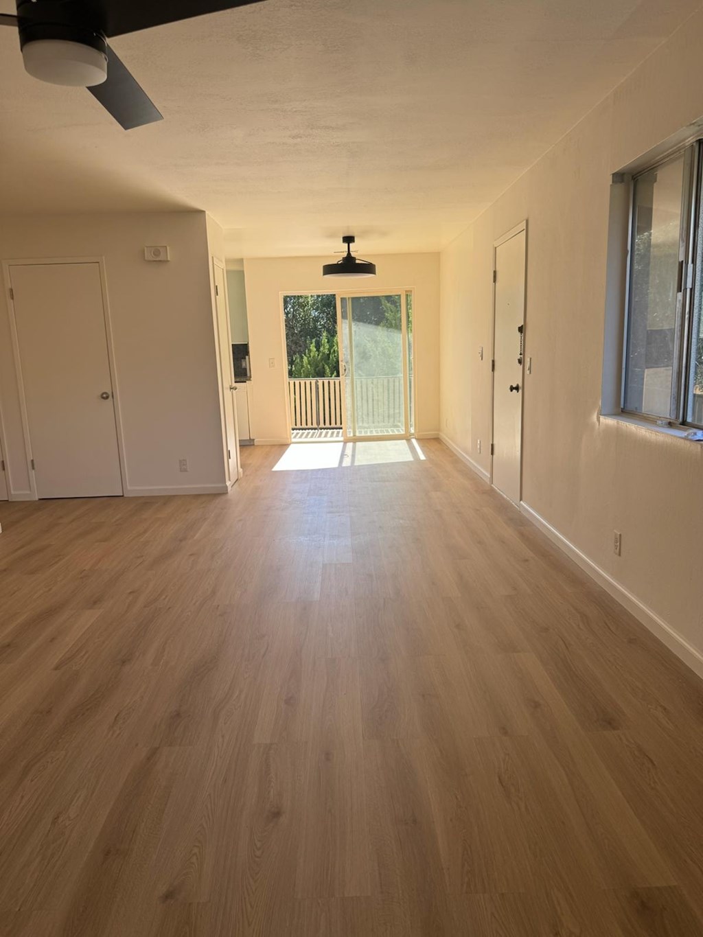 A long hallway with a ceiling fan and light fixture.