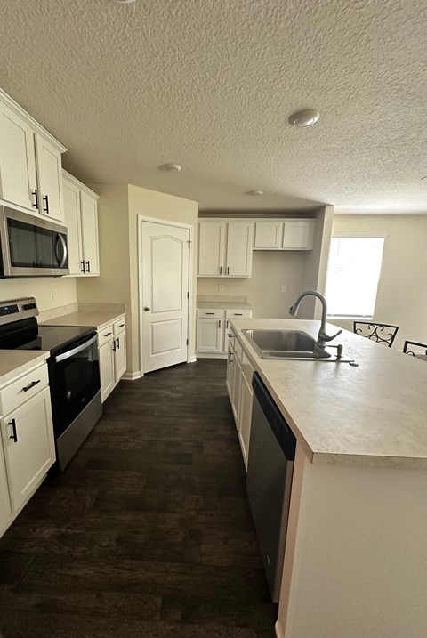 A kitchen with white cabinets and a black counter top.
