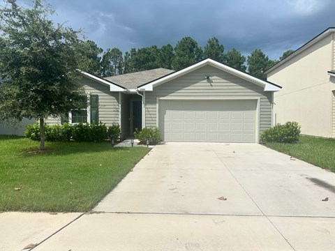 A house with a grey garage door and a tree in front.