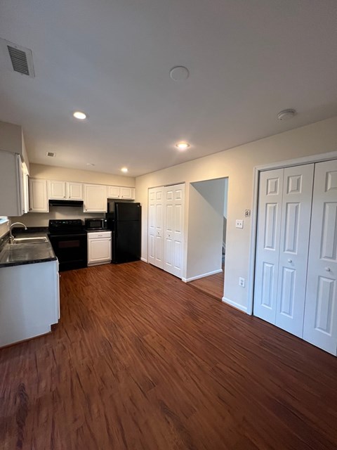 A kitchen with black appliances and white cabinets.