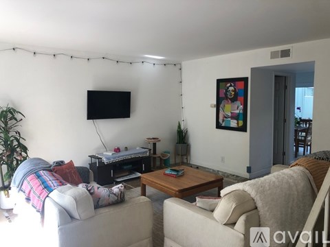 A living room with a grey couch, a wooden coffee table, a flat screen TV, and a painting on the wall.