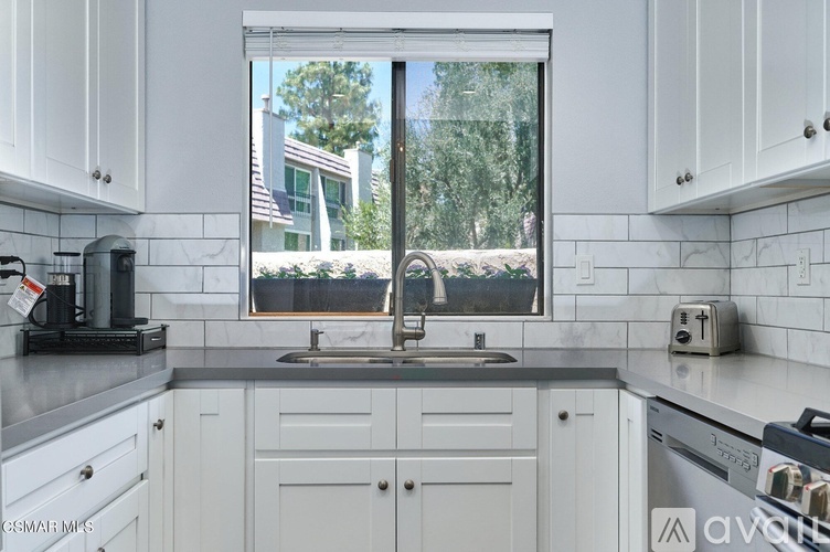 A kitchen with white cabinets and a black toaster on the counter.
