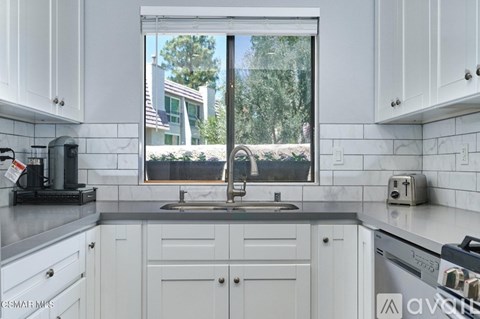 A kitchen with white cabinets and a black toaster on the counter.