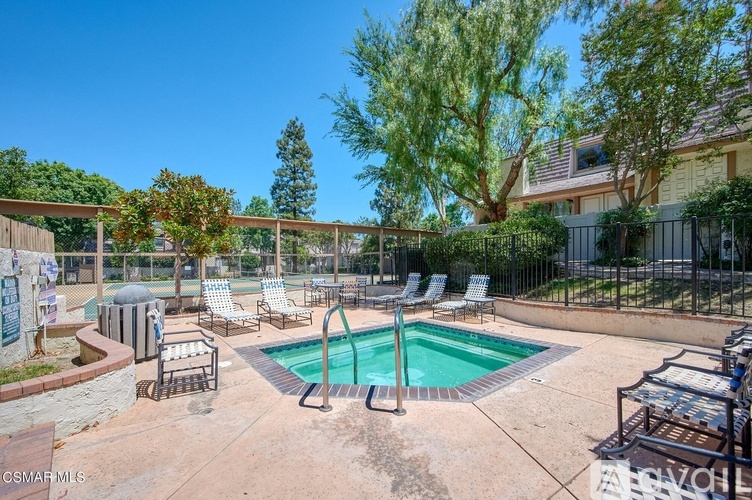 A pool area with chairs and a hot tub.