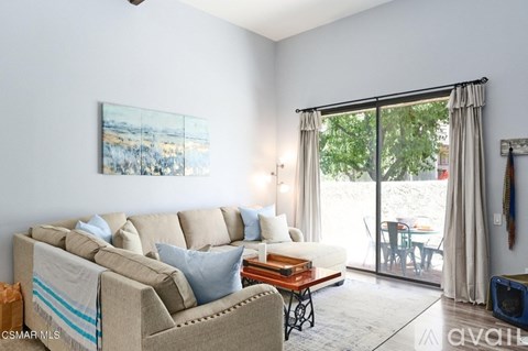 A living room with a beige couch, a coffee table, and a painting on the wall.