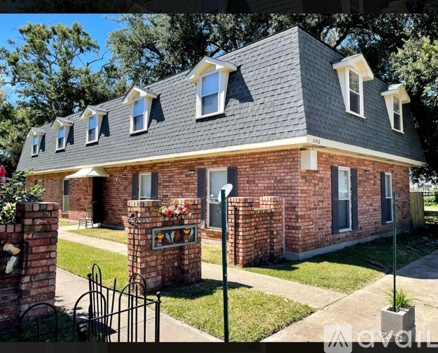 A brick house with a black iron gate in front.