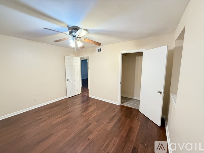 A room with a ceiling fan and wooden flooring.