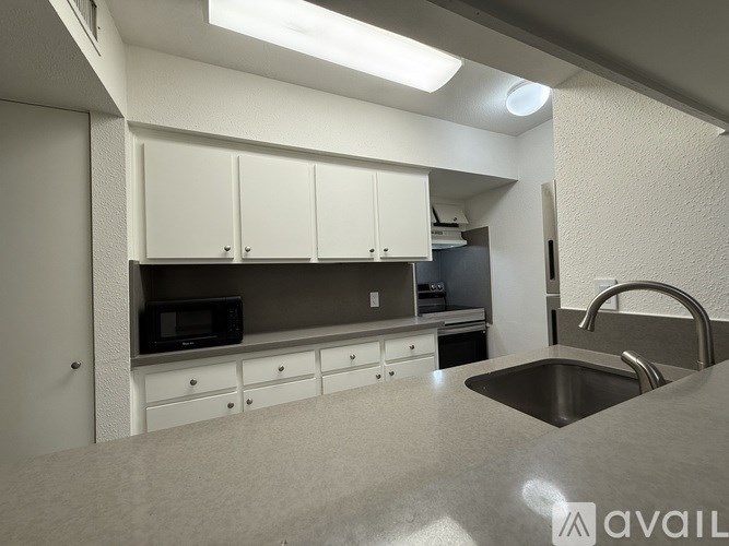 A kitchen with white cabinets and a stainless steel sink.