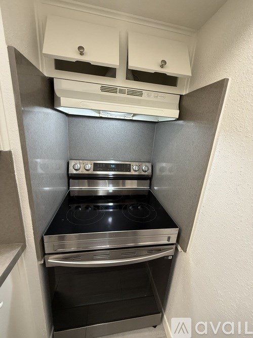 A small kitchen with a stove top oven and a range hood above it.