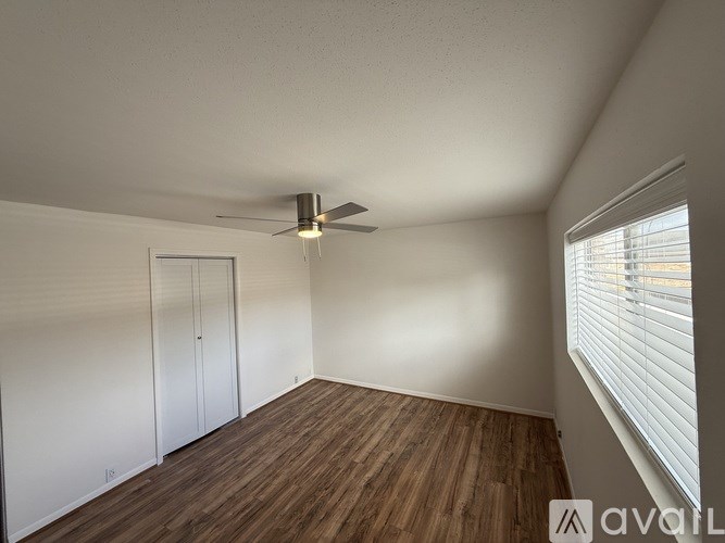 A room with a ceiling fan and wooden flooring.