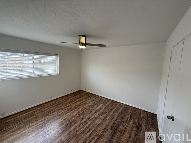 A room with wooden flooring and a window with blinds.