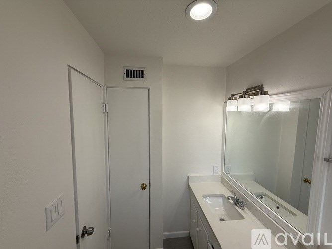 A bathroom with a sink, mirror, and a door.