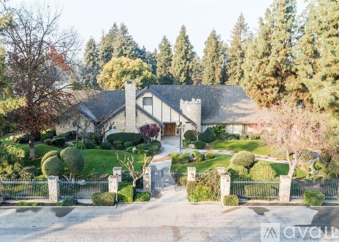 A large house with a driveway and a fence in front of it.