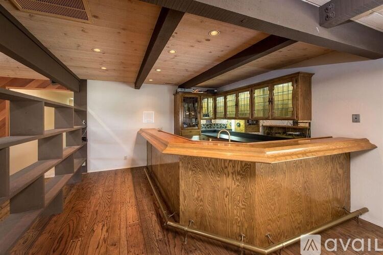 A wooden bar with a counter and shelves on the left side.