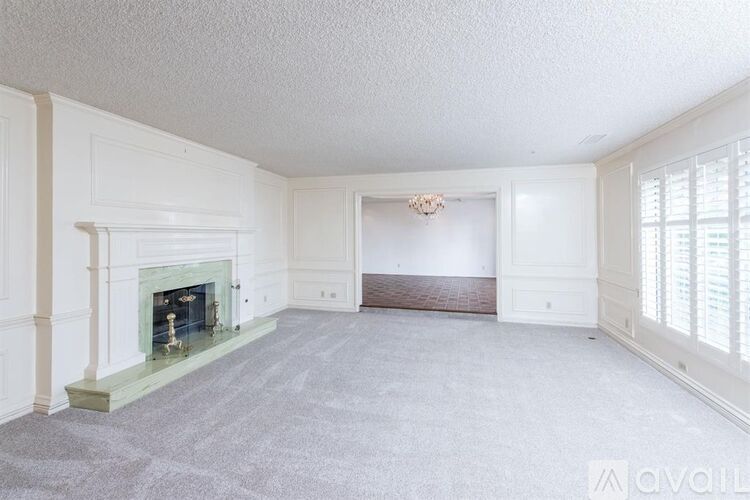 A spacious living room with a fireplace and a chandelier.