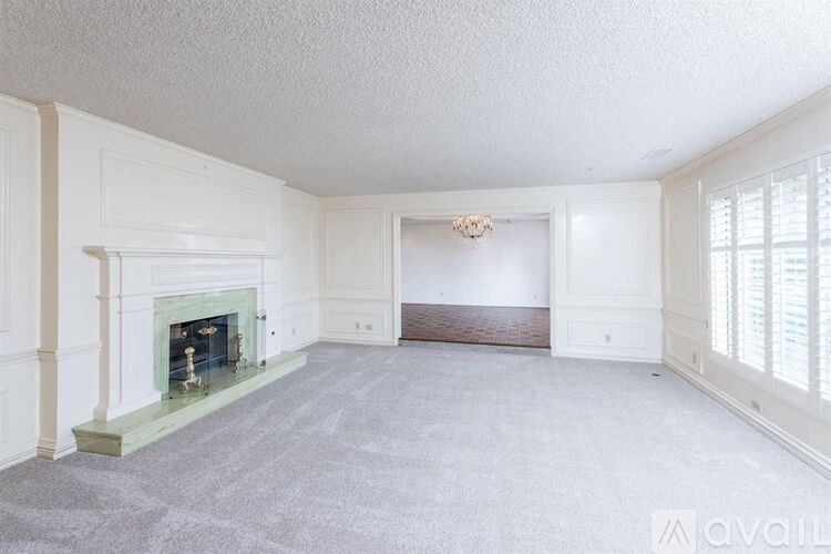 A spacious living room with a fireplace and a chandelier.