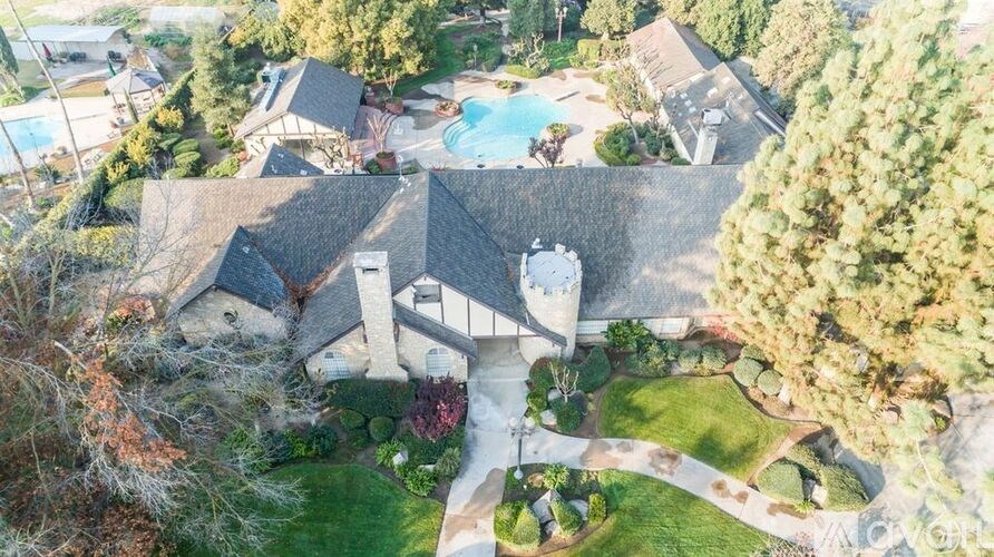 A large house with a swimming pool surrounded by a well-manicured lawn.