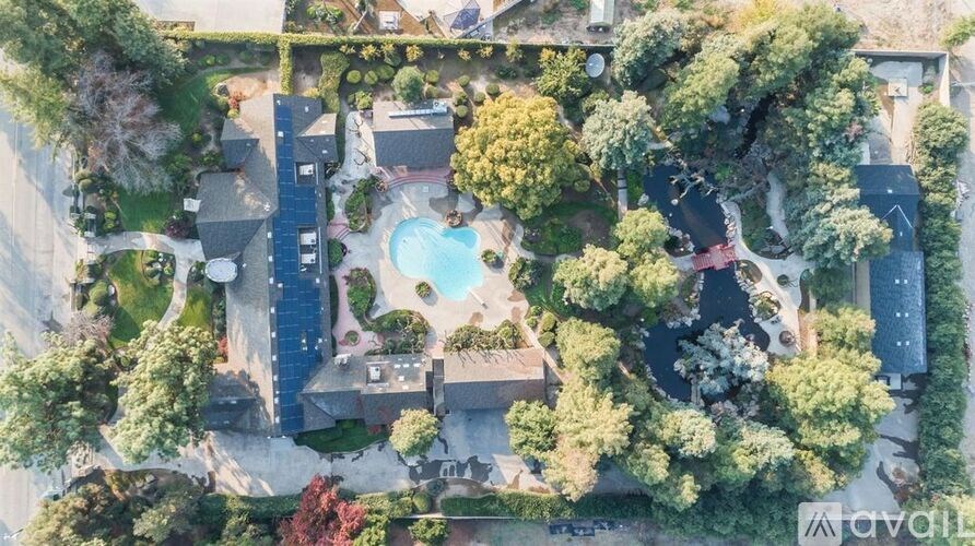 A bird's eye view of a house with a swimming pool surrounded by trees.