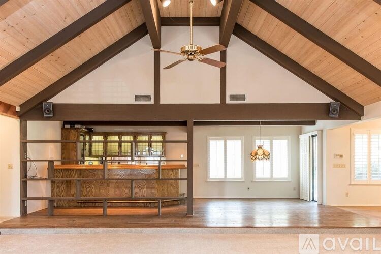 A spacious room with a wooden ceiling and a bar area.