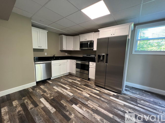 A kitchen with wood flooring and stainless steel appliances.