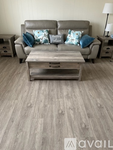 A grey couch with a wooden coffee table in front of it.