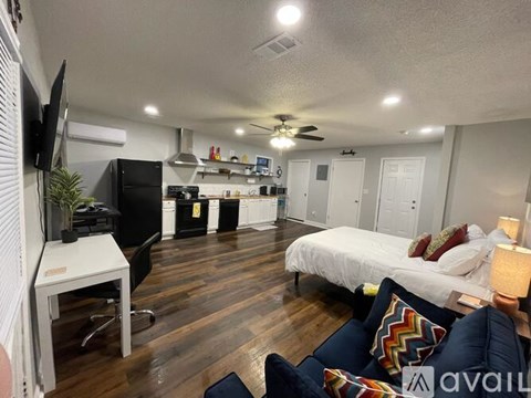 A living room with a couch and a bed in the background.