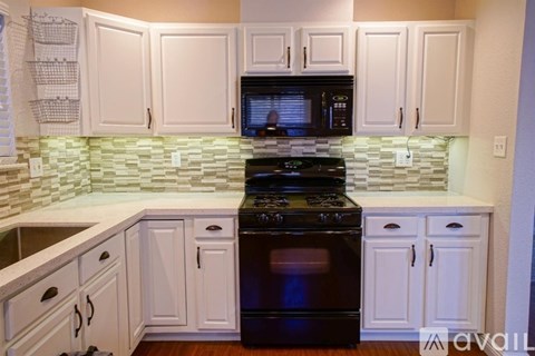 A kitchen with white cabinets and a black stove top oven.