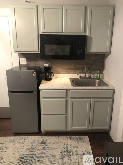 A kitchen with a black microwave above a stainless steel sink.
