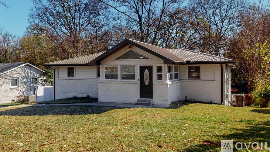 A small white house with a brown roof is for sale.