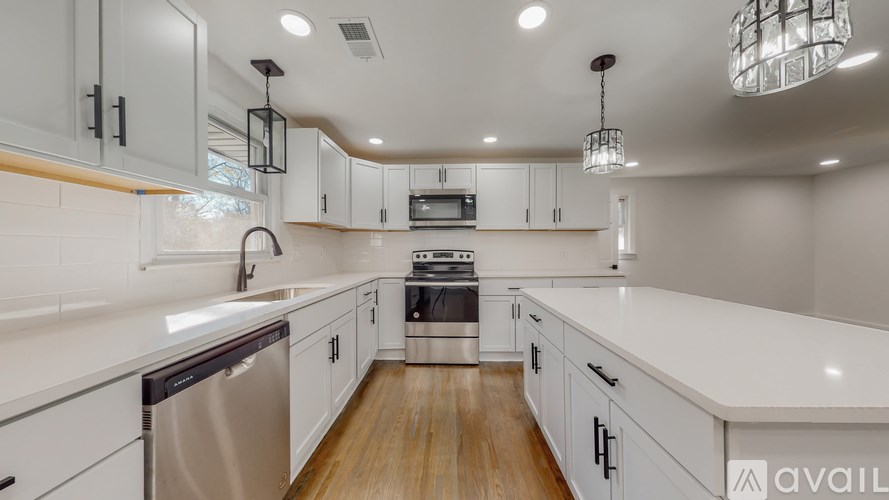 A modern kitchen with white cabinets and a wooden floor.