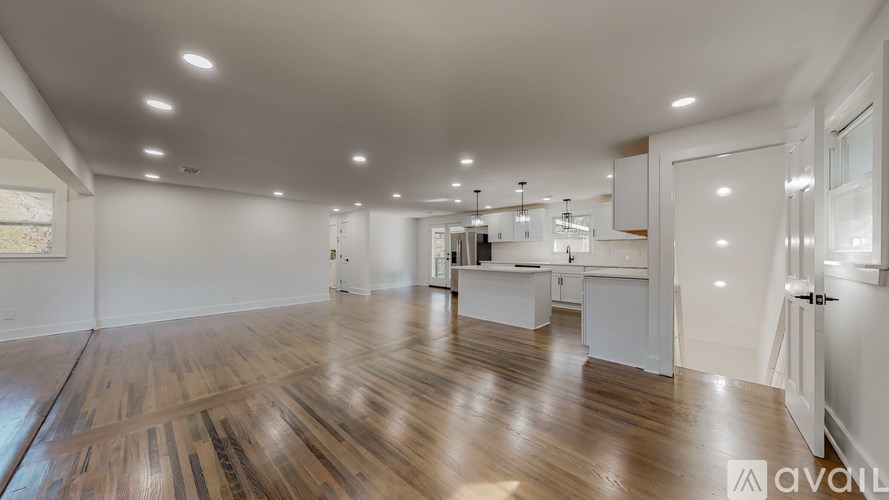 A spacious room with wooden flooring and white walls.
