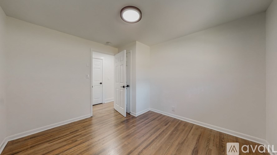 A room with wooden floors and white walls with two doors.