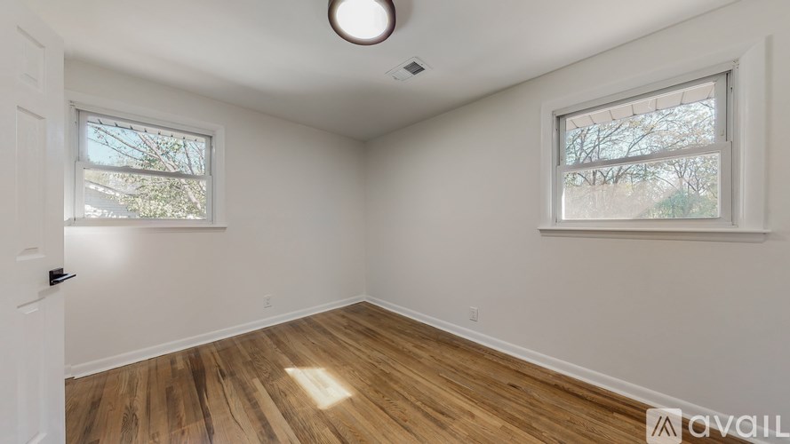 A room with wooden floors and two windows.