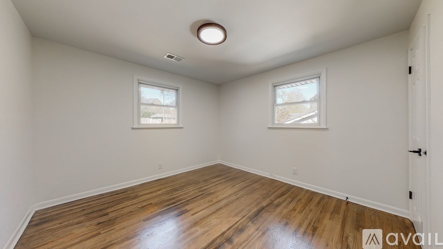 A room with wooden floors and two windows.