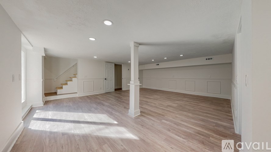 A spacious room with wooden flooring and white walls.