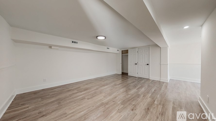 A spacious room with wooden flooring and white walls.