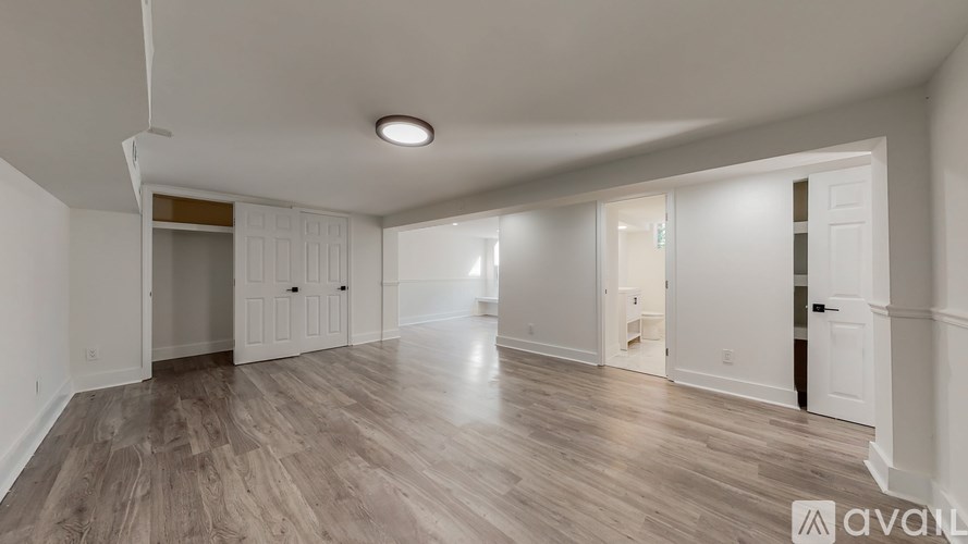 A spacious room with wooden flooring and white walls.