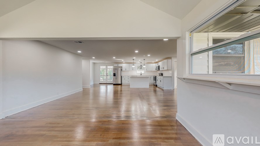 A spacious room with wooden flooring and white walls.